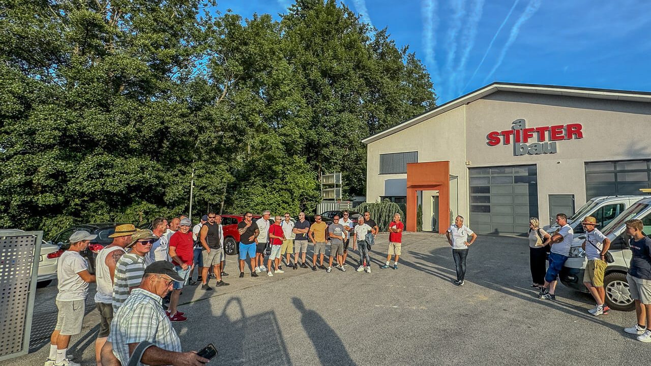 Mitarbeiter der aSTIFTERbau GmbH versammeln sich zum Start des Betriebsausflugs vor dem Firmengebäude.